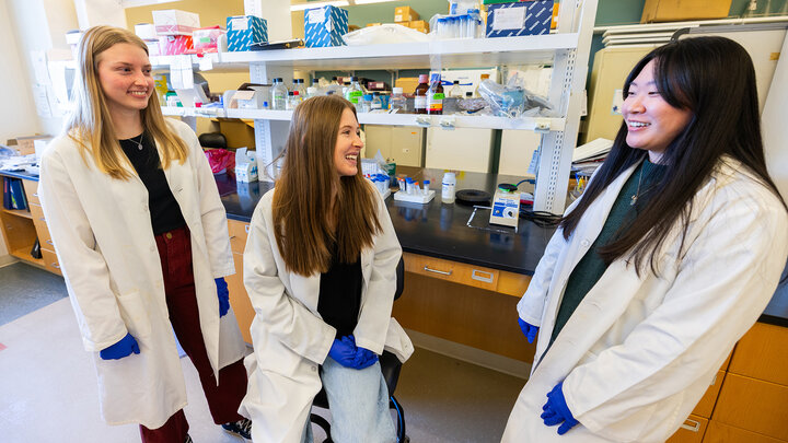 University of Nebraska–Lincoln undergraduates (from left) Avery Marquis, Vanessa Hubing and Chanasei Ziemann pose in lab coats for a photo in Luwen Zhang’s campus lab. The students are first co-authors on two research papers published recently in the Journal of Medicine Virology. Their work explores how key immune systems have adapted over time.